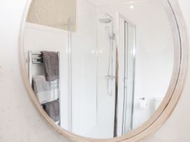 A bathroom with a shower enclosure a toilet and a towel rack with towels at Gerrard House Apartment in Llandudno
