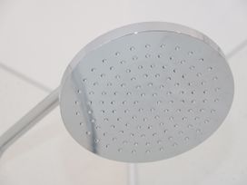 A close up of a round metal shower head attached to a wall in a bathroom at Gerrard House Apartment in Llandudno