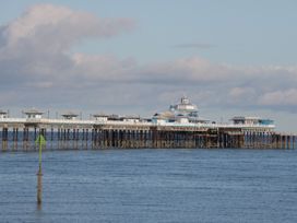 A pier with buildings extending over the sea under a cloudy sky at Gerrard House Apartment in Llandudno