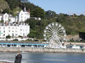 A waterfront with a Ferris wheel and white buildings in front of a hillside at Gerrard House Apartment in Llandudno