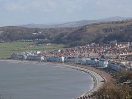 A curved coastline with a promenade and buildings next to hills at Gerrard House Apartment in Llandudno