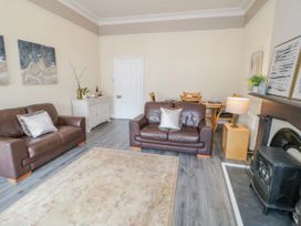 A living room with two brown leather sofas a dining table and chairs a rug and a fireplace at Gerrard House Apartment in Llandudno