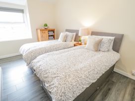 A bedroom with two single beds a wooden cabinet and a lamp at Gerrard House Apartment in Llandudno