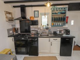 A kitchen with appliances and dishes in cabinets at Menuchah in Criccieth
