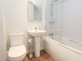 A bathroom with a toilet and sink next to a bathtub with a shower at Corvesgate in Nottington near Weymouth