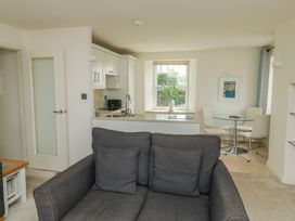 A living room with a sofa and kitchen area at Bay View in Brixham