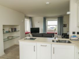 A kitchen with a sink and a living area with a sofa and television at Bay View in Brixham