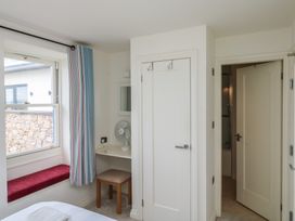 A bedroom with a window, fan and table at Bay View in Brixham