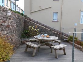 An outdoor dining area with a wooden table and chairs at Bay View in Brixham