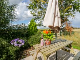 A table with flowers and a bottle at Howgills Retreat Gatebeck near Kirkby Lonsdale