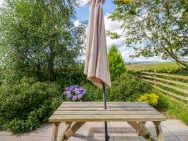 An outdoor seating area with a table and a parasol at Howgills Retreat Gatebeck near Kirkby Lonsdale