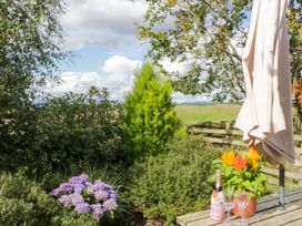 A table with a bottle and glasses surrounded by flowers at Howgills Retreat Gatebeck near Kirkby Lonsdale