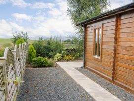 An outdoor view of a wooden cabin with a pathway and plants at Howgills Retreat Gatebeck near Kirkby Lonsdale