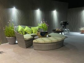 An outdoor seating area with cushions and a grill at Ninky Nonk in Bishop Sutton