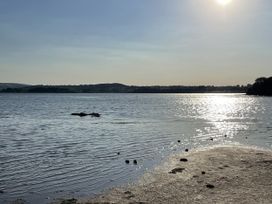 A lake with sunlight reflections and distant hills at Ninky Nonk in Bishop Sutton