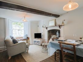 A living room with a sofa, television, and dining table at The Nest in Lyme Regis