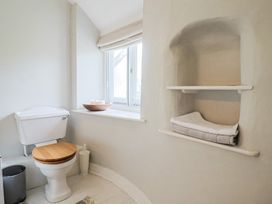 A bathroom with a toilet and shelves holding towels at The Nest in Lyme Regis