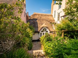 A garden with a thatched cottage and pathway at The Nest in Lyme Regis