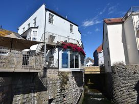 A building with a balcony and flowers over a waterway at The Nest in Lyme Regis