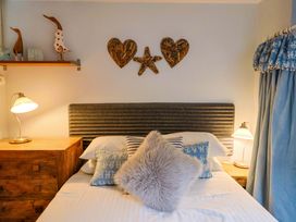 A bedroom with a bed, pillows, a lamp, and decorative items at Seaside in Lyme Regis