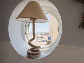 A lamp by a circular window overlooking the harbor at Seaside in Lyme Regis