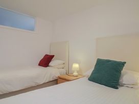 A bedroom with two beds and a lamp on a nightstand at Greystones Flat in Lyme Regis