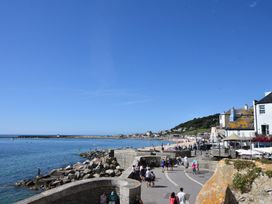 A seaside view with a beach and people walking at Greystones Flat in Lyme Regis