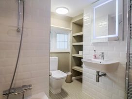 A bathroom with a shower, toilet, sink, and shelves at Maries in Lyme Regis