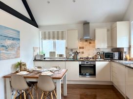 A kitchen with a dining table and appliances at 11 The Gables in Lyme Regis