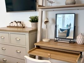 A living room with a television and a desk at 11 The Gables in Lyme Regis