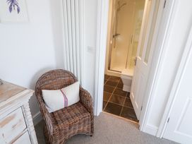 A bathroom with a shower and toilet seen from an adjacent room at Seagull in Lyme Regis