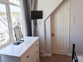 A bedroom with a dresser and a television mounted on the wall at Watersmeet Lyme Regis