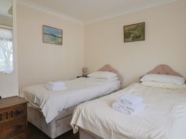 A bedroom with two single beds and artwork on the walls at Gosling Way Lyme Regis