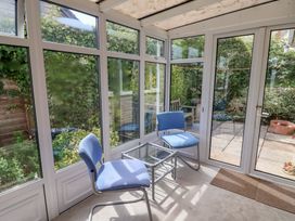 A conservatory with a glass table and chairs at Gosling Way in Lyme Regis