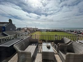 A balcony with chairs and a table overlooking the sea at 8 Bowling Green Chalets in Lyme Regis