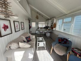 A living room with a sofa, coffee table, kitchen and dining area at 8 Bowling Green Chalets Lyme Regis
