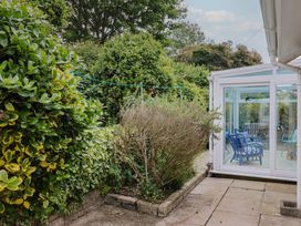 A garden with a conservatory and greenery at High Trees in Lyme Regis