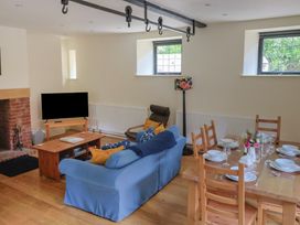 A living room with a sofa, television, and dining table at Yard Cottage in Rousdon