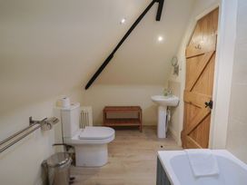 A bathroom containing a toilet, sink, and bath at Yard Cottage in Rousdon