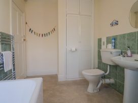 A bathroom with a bathtub, toilet, sink, and storage cabinet at Greystones Lyme Regis