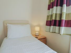 A bedroom with a bed and a lamp on the bedside table at Greystones Lyme Regis