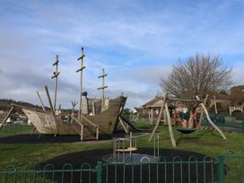 A playground with a pirate ship structure and swings at Greystones Lyme Regis
