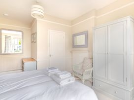 A bedroom with a bed, wardrobe, and mirror at 2 Hadleigh Villas in Lyme Regis