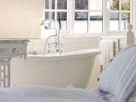 A bathroom with a bathtub and towel rack at 2 Hadleigh Villas in Lyme Regis