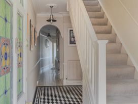 A hallway with a staircase and stained glass door at 2 Hadleigh Villas Lyme Regis