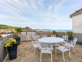 An outdoor terrace with a round table and chairs at 2 Hadleigh Villas in Lyme Regis