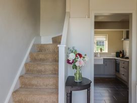 A hallway with a staircase leading to upper floors and a view into the kitchen at Westhaven in Lyme Regis