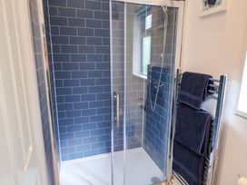 A shower with glass door and towels on a rack at High Bullen Lodge in Morcombelake