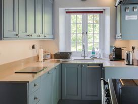 A kitchen with blue cabinets a countertop with various appliances and a window above the sink at Lynch Cottage in Rousdon
