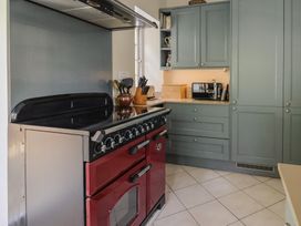 A kitchen with a red oven and grey cabinets with a microwave and knife block on the countertop at Lynch Cottage in Rousdon